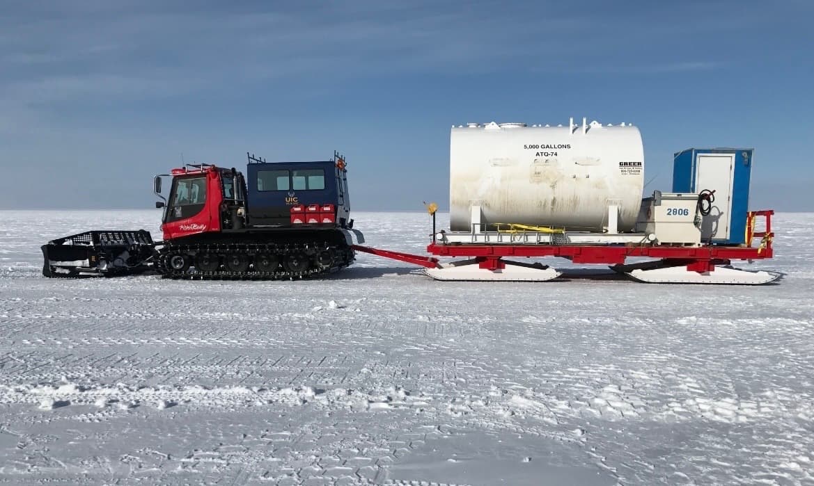 A tank secured on a sled pulled by a tracked prime mover.