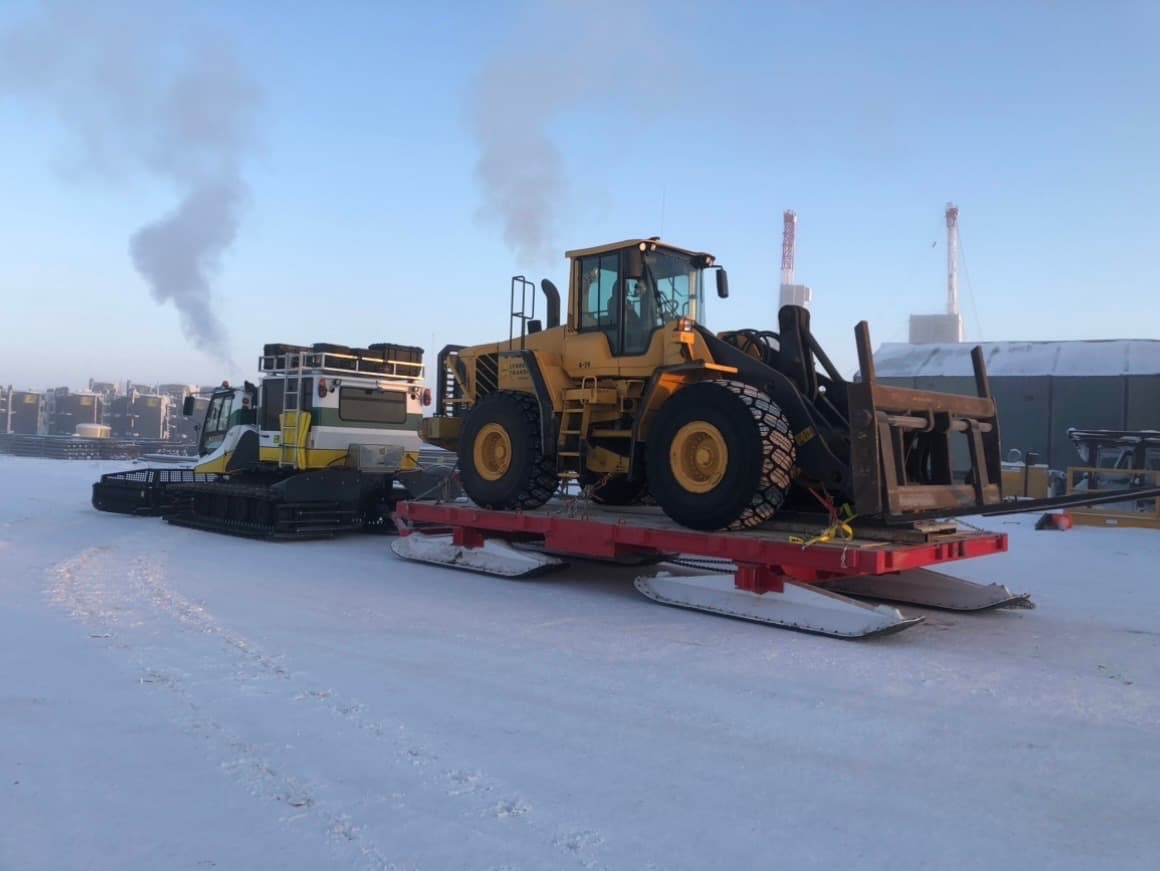 A Volvo wheel loader with forks on a Mammoth sled at dusk.