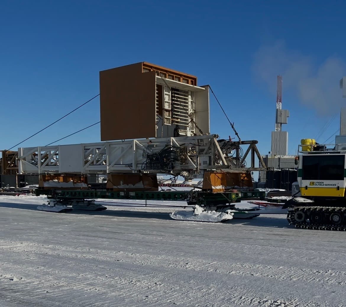 A framed drilling module on a Mammoth sled being pulled by a tracked prime mover.